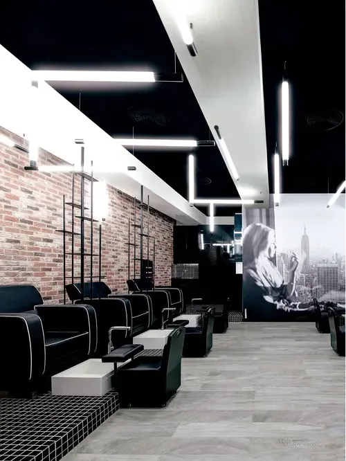 The loft's dark studio with neon strip lighting, brick wall and pedicure benches