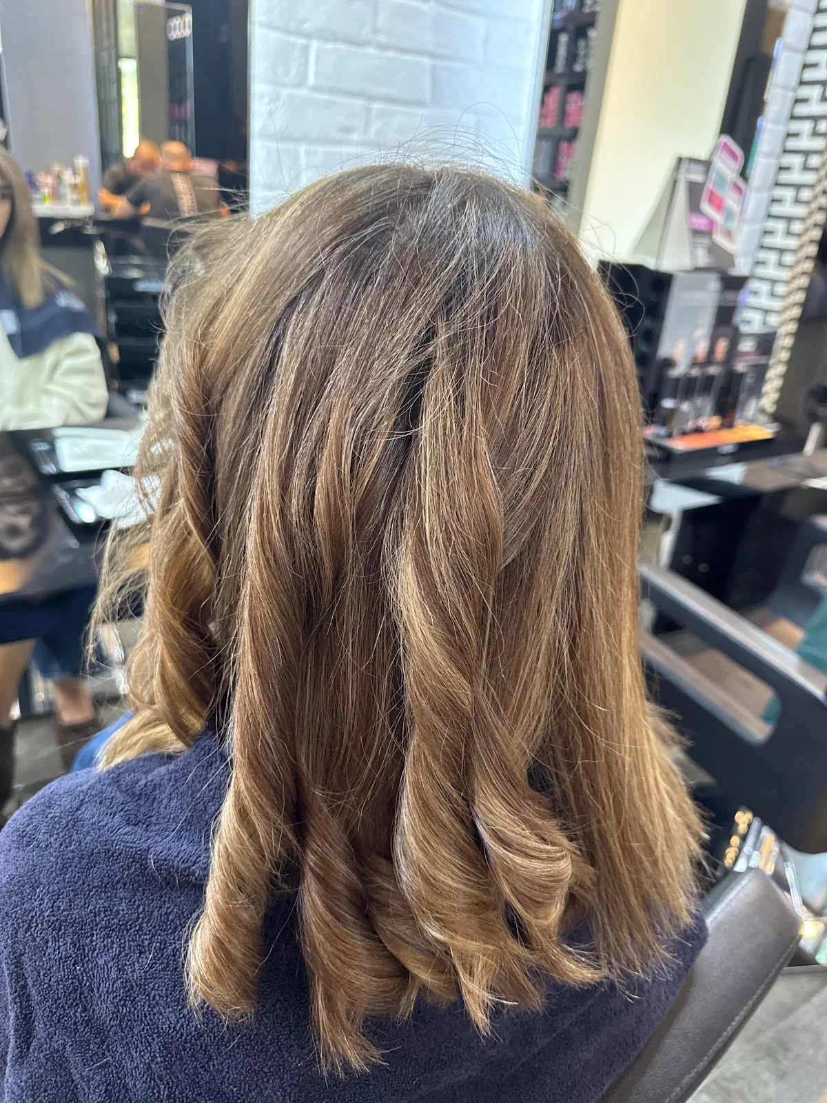 Freshly styled glossy waves seen from behind in the salon