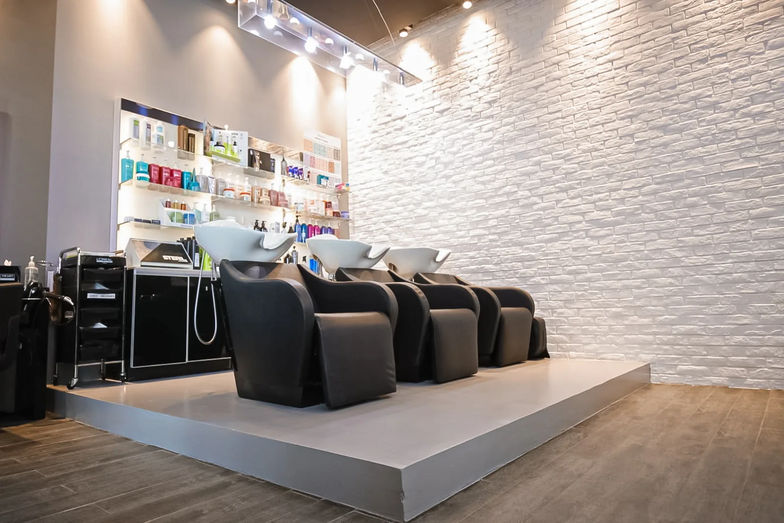 Wash and shampoo stations on a raised platform against white brick