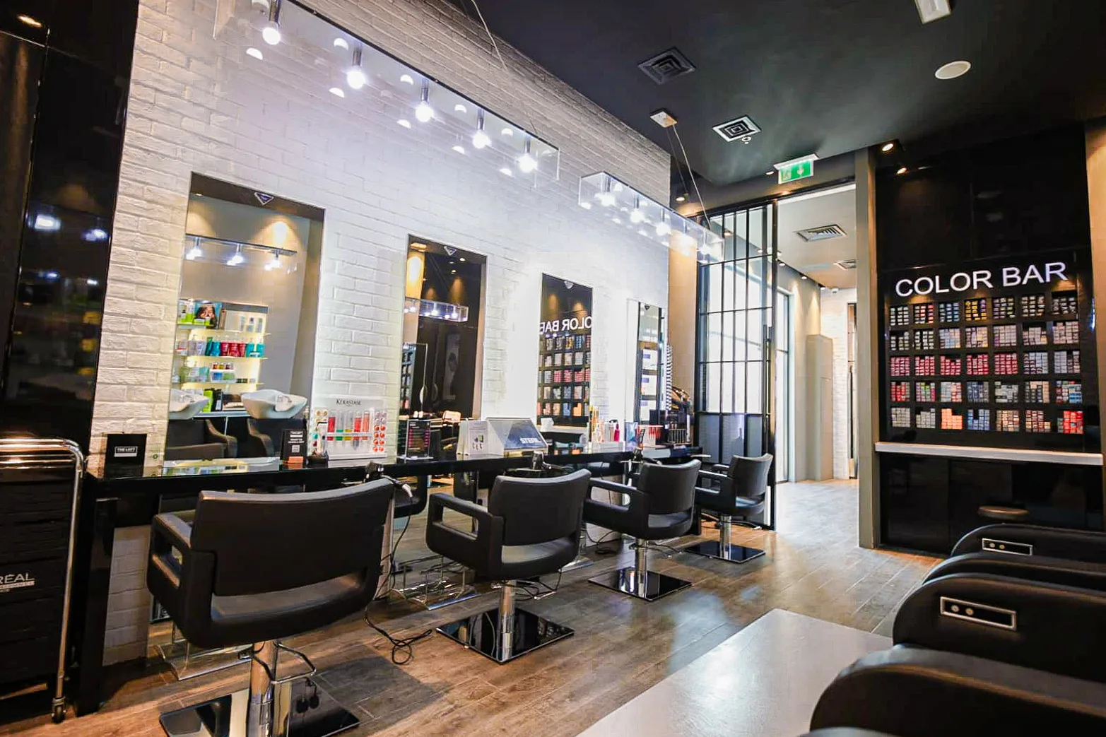 Interior of The Loft Fifth Avenue: styling chairs along a white exposed-brick wall beside the Color Bar