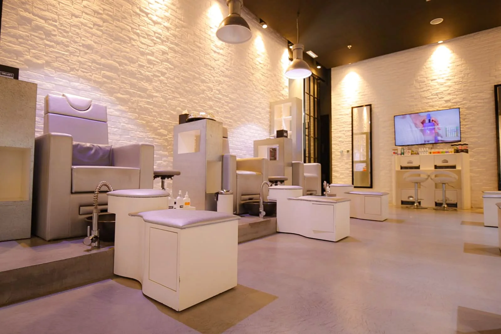 Bright pedicure area with pendant lighting and a wall of nail colours