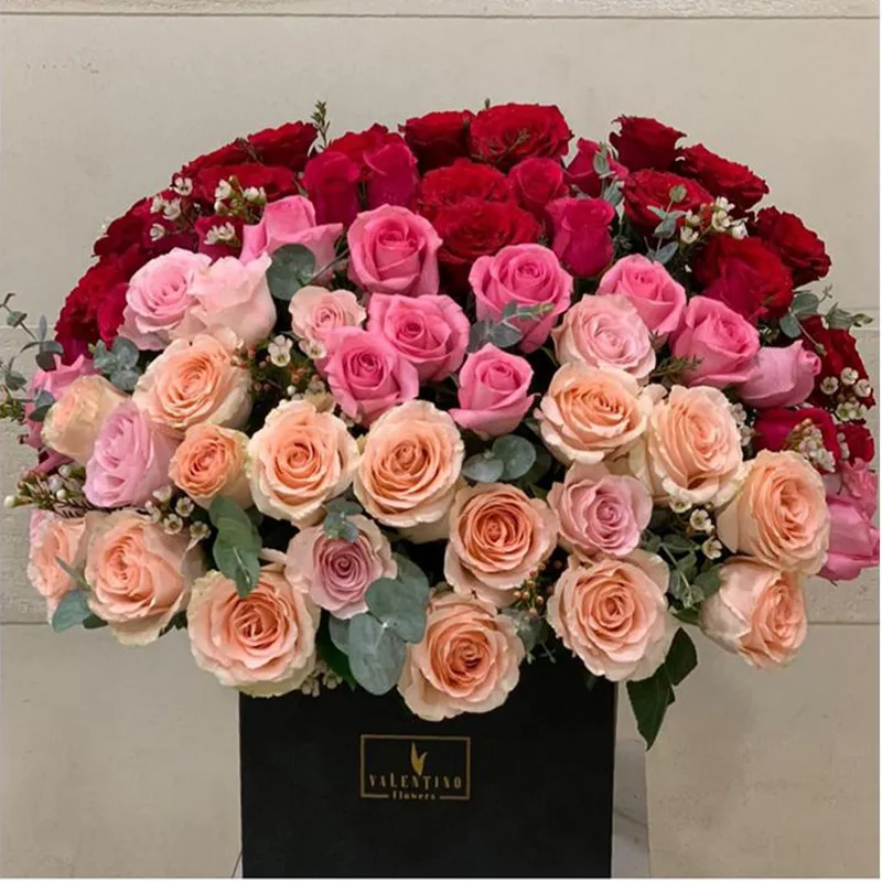 Peach and red roses arranged in a black box