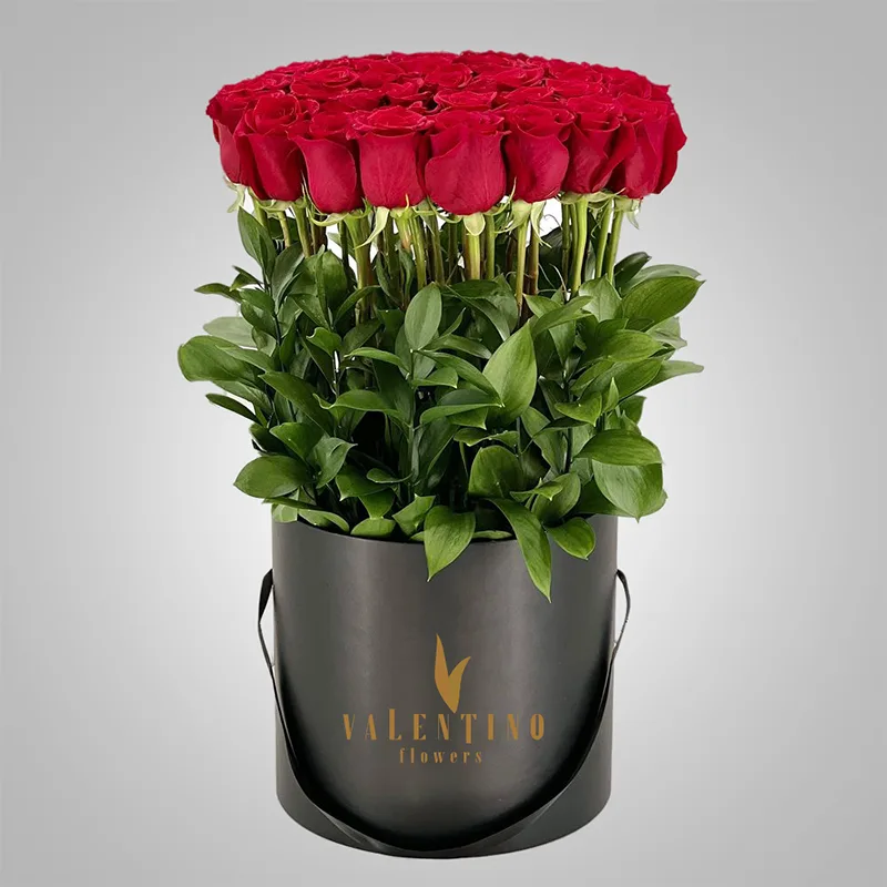 Tall standing red roses with greenery in a black Valentino box