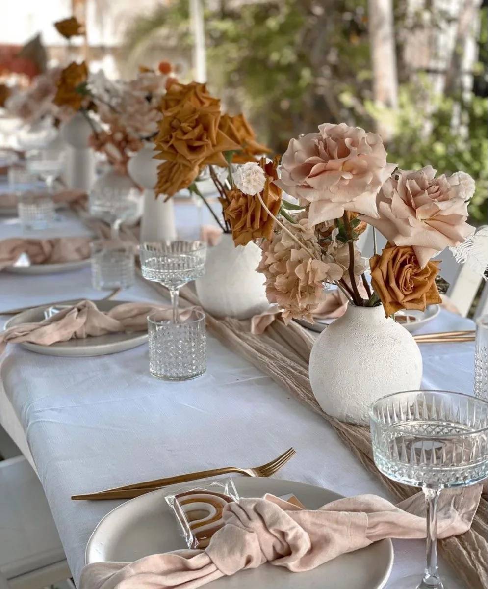 Boho tablescape with terracotta and peach roses in white vases