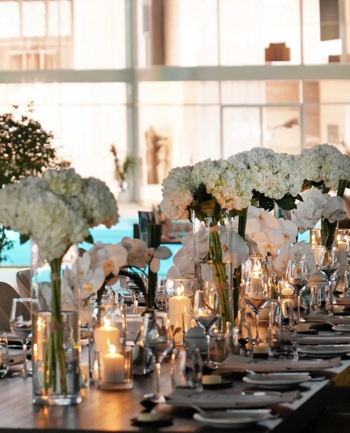 Long event table styled with white hydrangea, orchids and candlelight