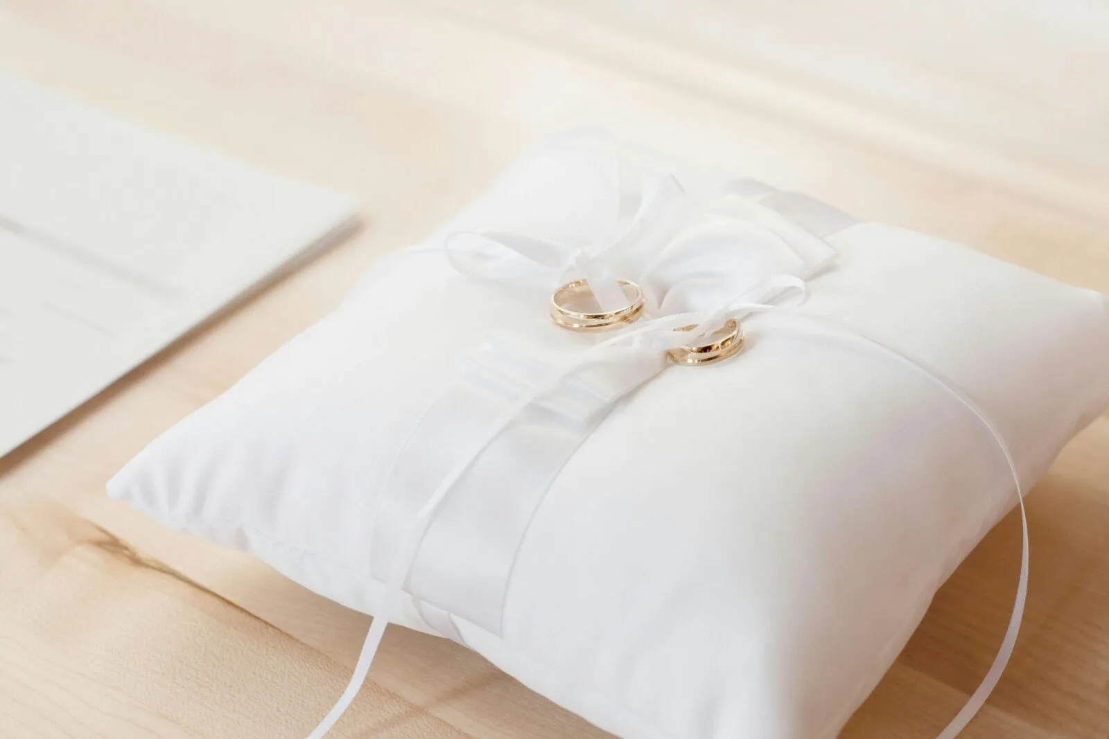 Pair of gold wedding bands resting on a white cushion