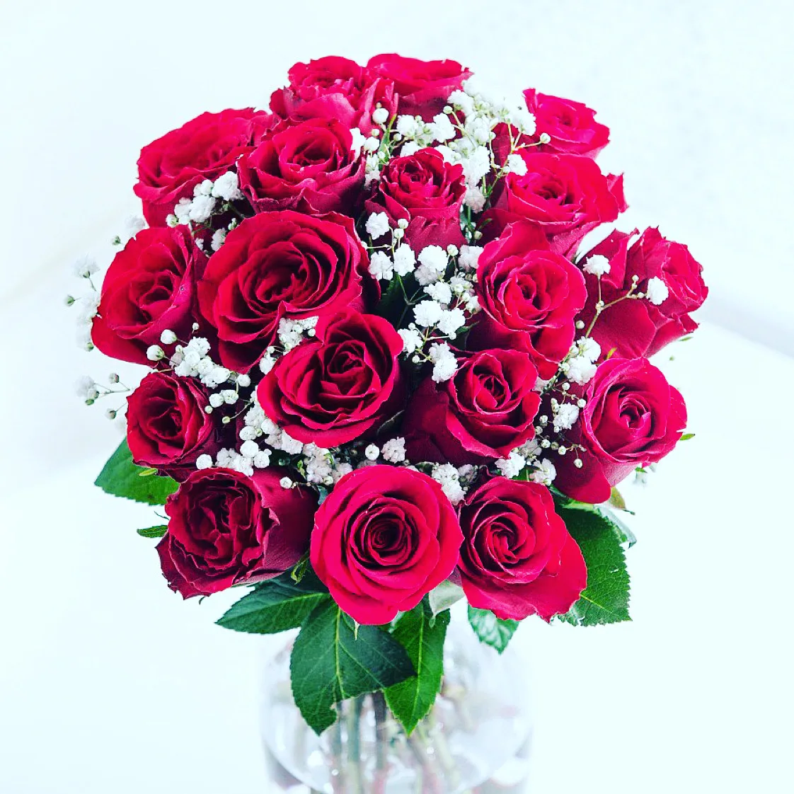 Bouquet of red roses with baby's breath in a glass vase