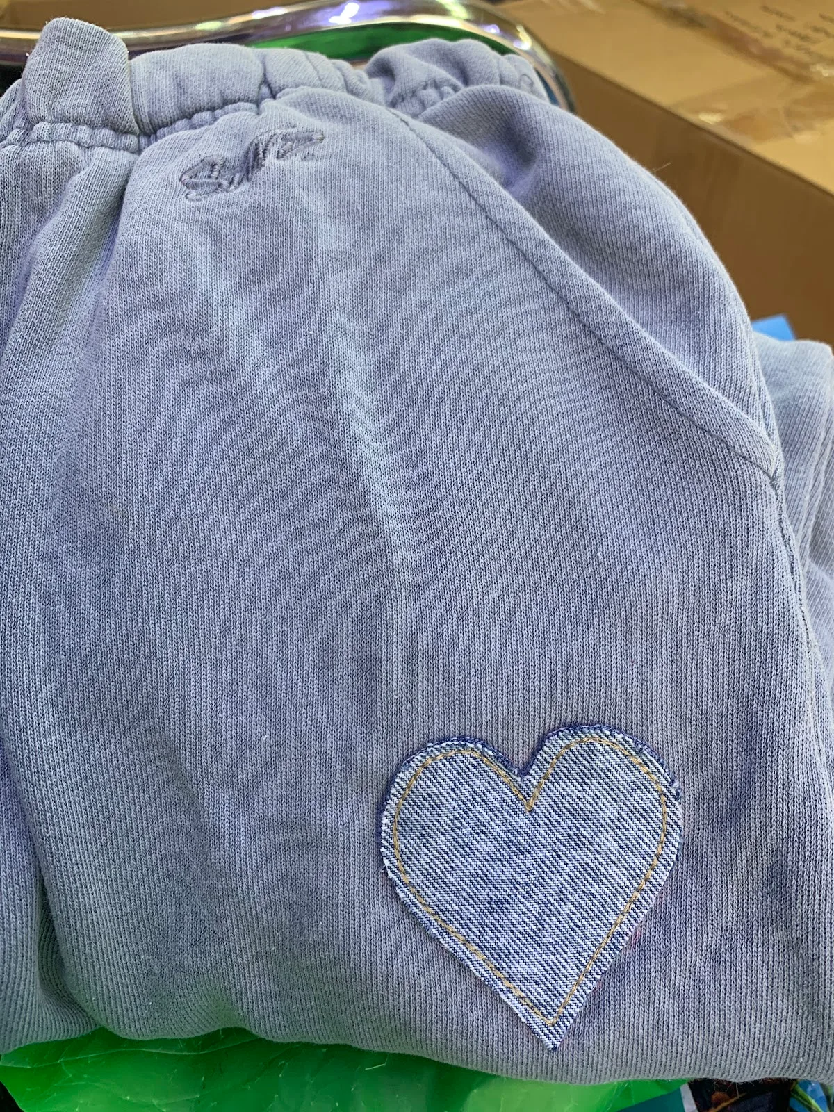 Lavender joggers mended with a hand-stitched denim heart patch.
