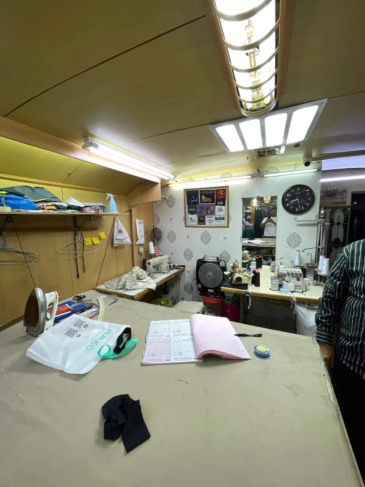Inside the Electra Tailoring workshop with sewing machines, threads and a pressing table.