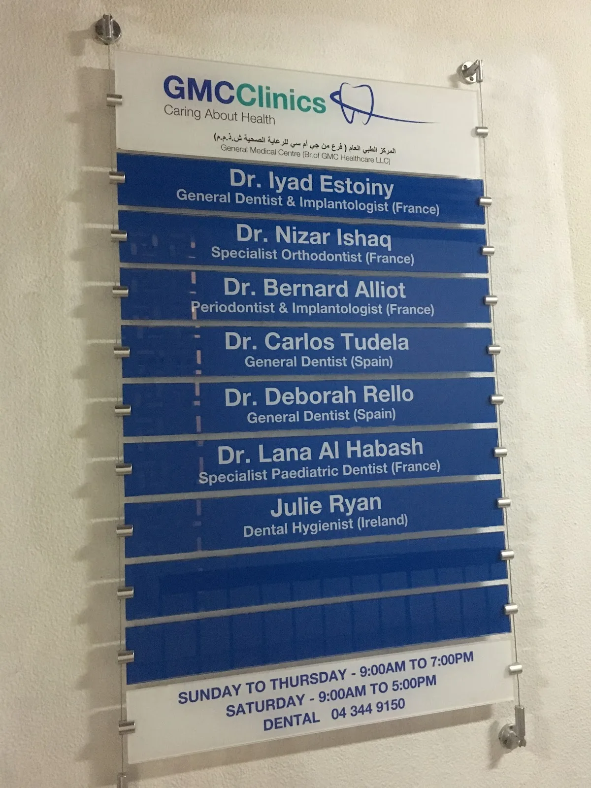 Dental team and opening hours board at the clinic