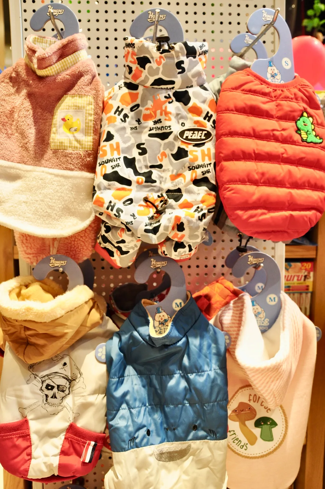 A rail of pet clothing and jackets in different colours