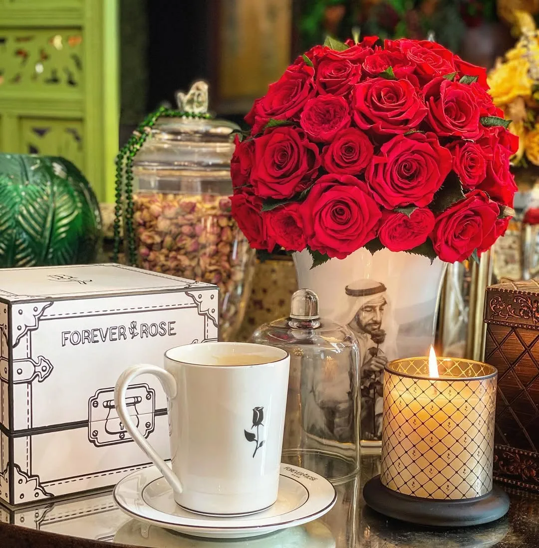 A Forever Rose café setting with a red rose bouquet, mug and candle