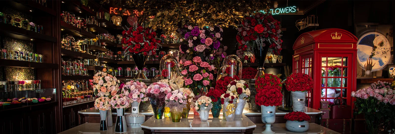 Wide view of the atelier interior with a gold-leaf canopy, red phone box and rose displays