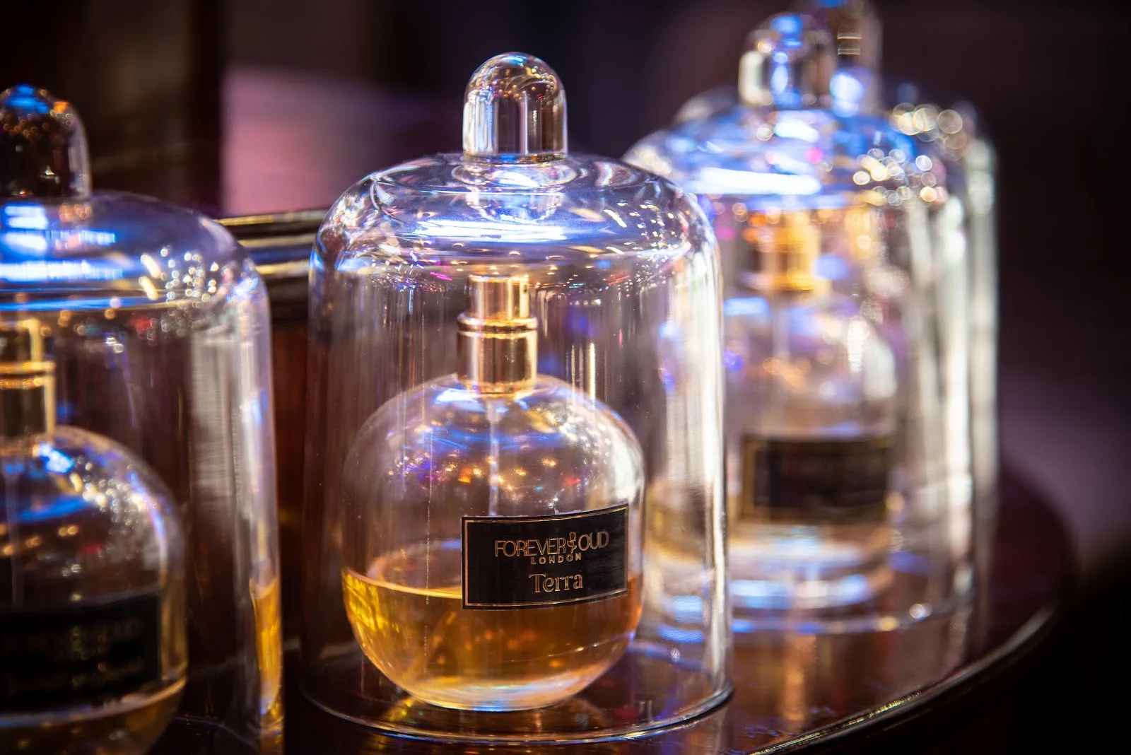 Forever Oud London fragrance bottles displayed under glass cloches