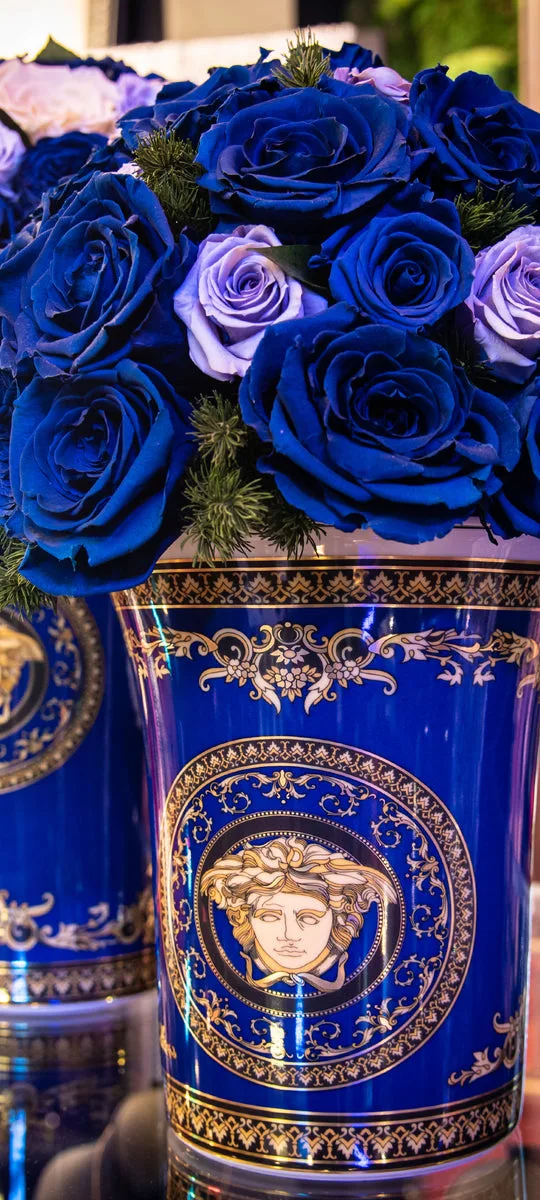 Deep blue and lilac roses arranged in an ornate blue and gold vase
