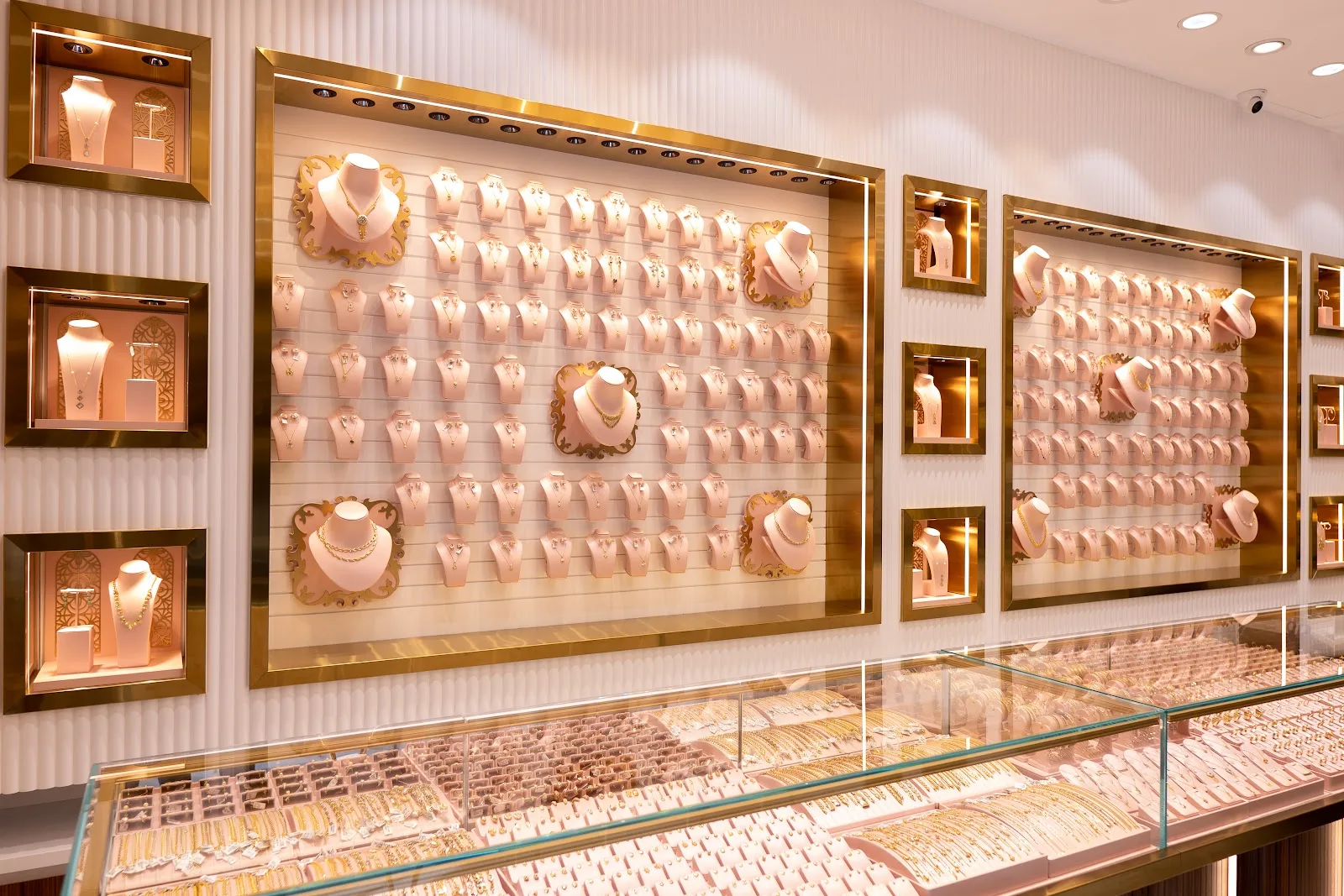 Wall of gold bridal jewellery on soft pink display busts