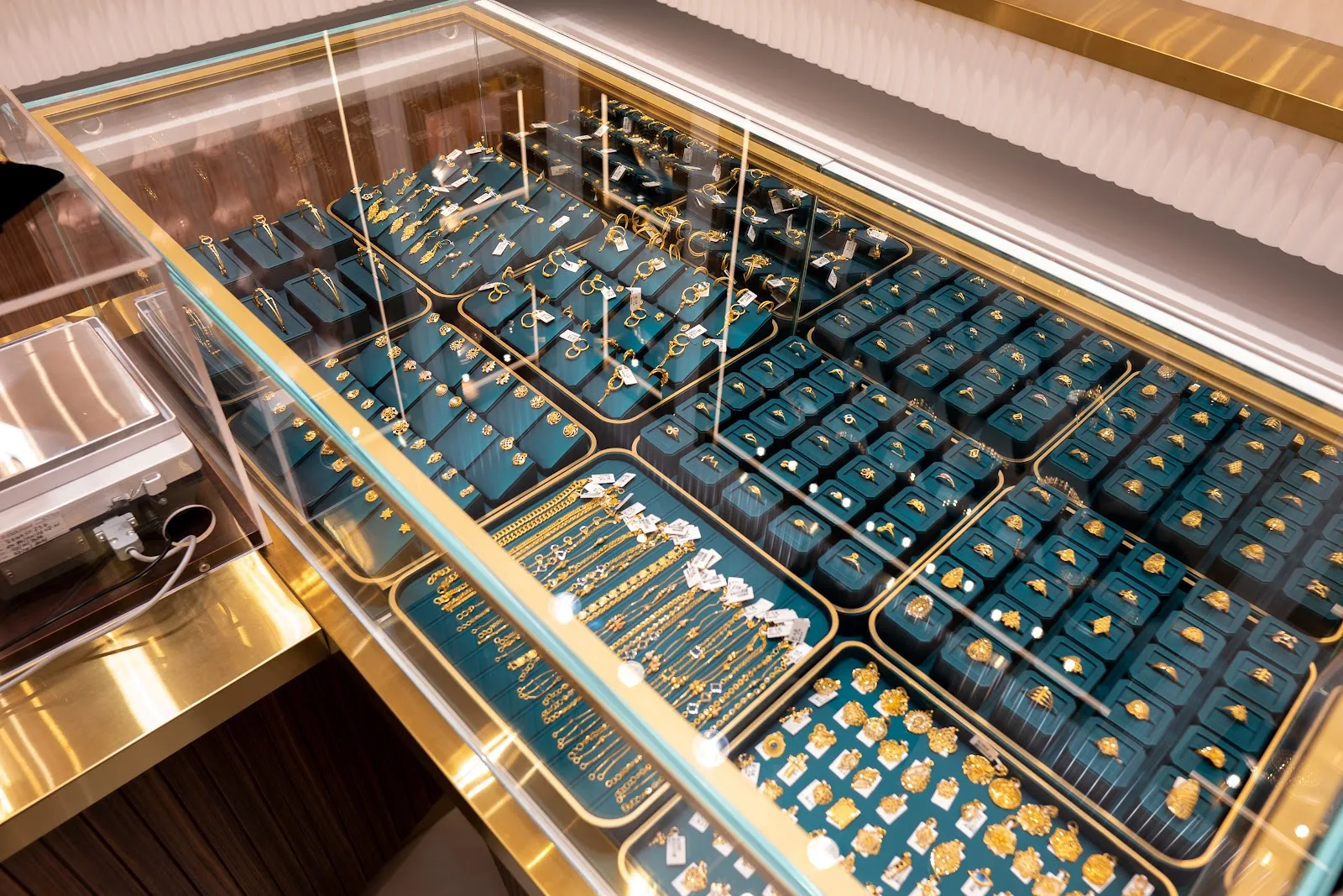 Top-down view of gold jewellery arranged on teal display trays