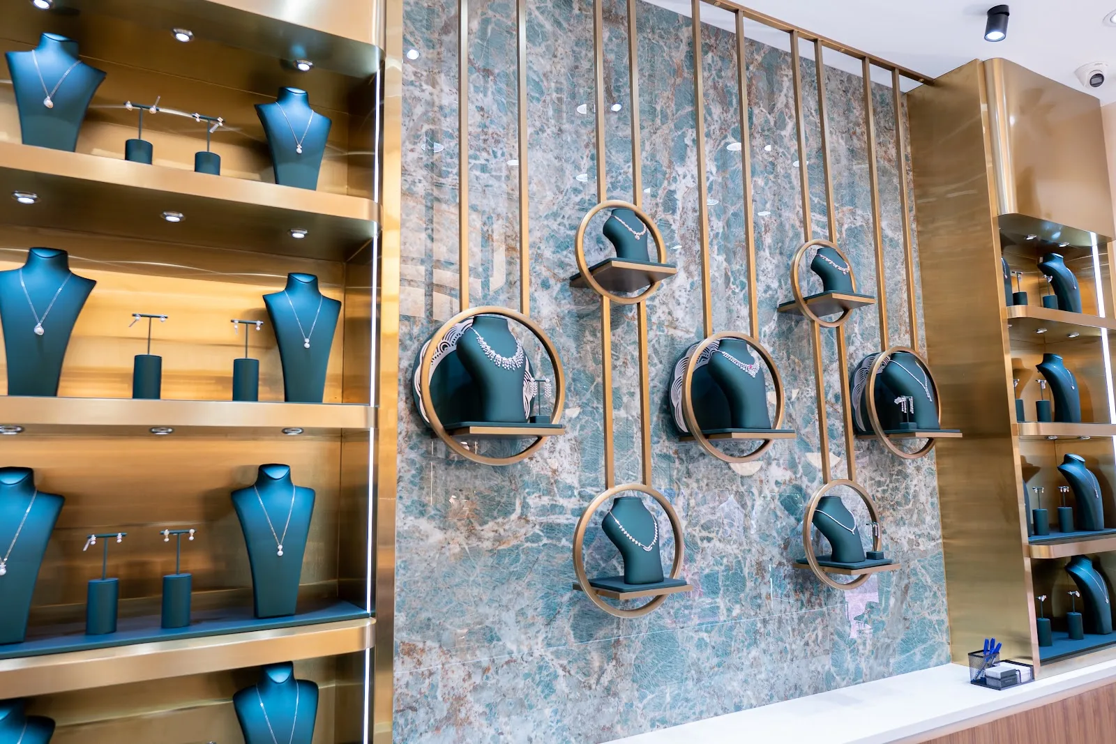 Thangals interior with necklaces displayed on green busts against a marble and brass wall
