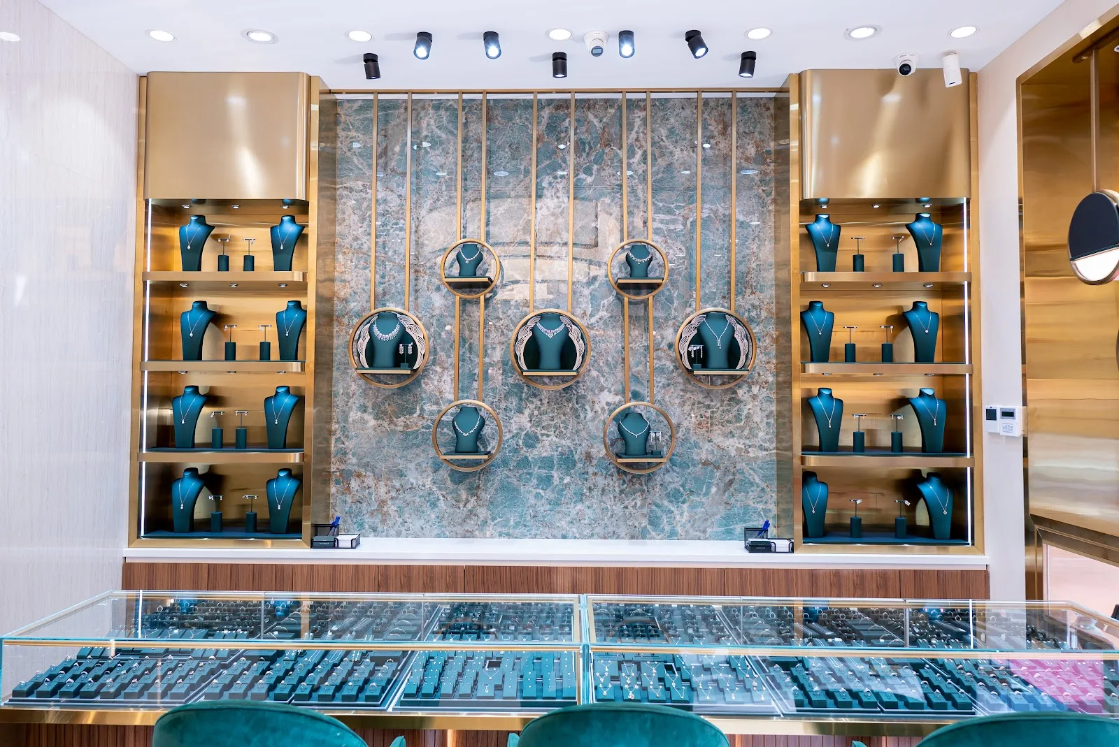 Feature wall of gold necklaces on green busts with brass detailing