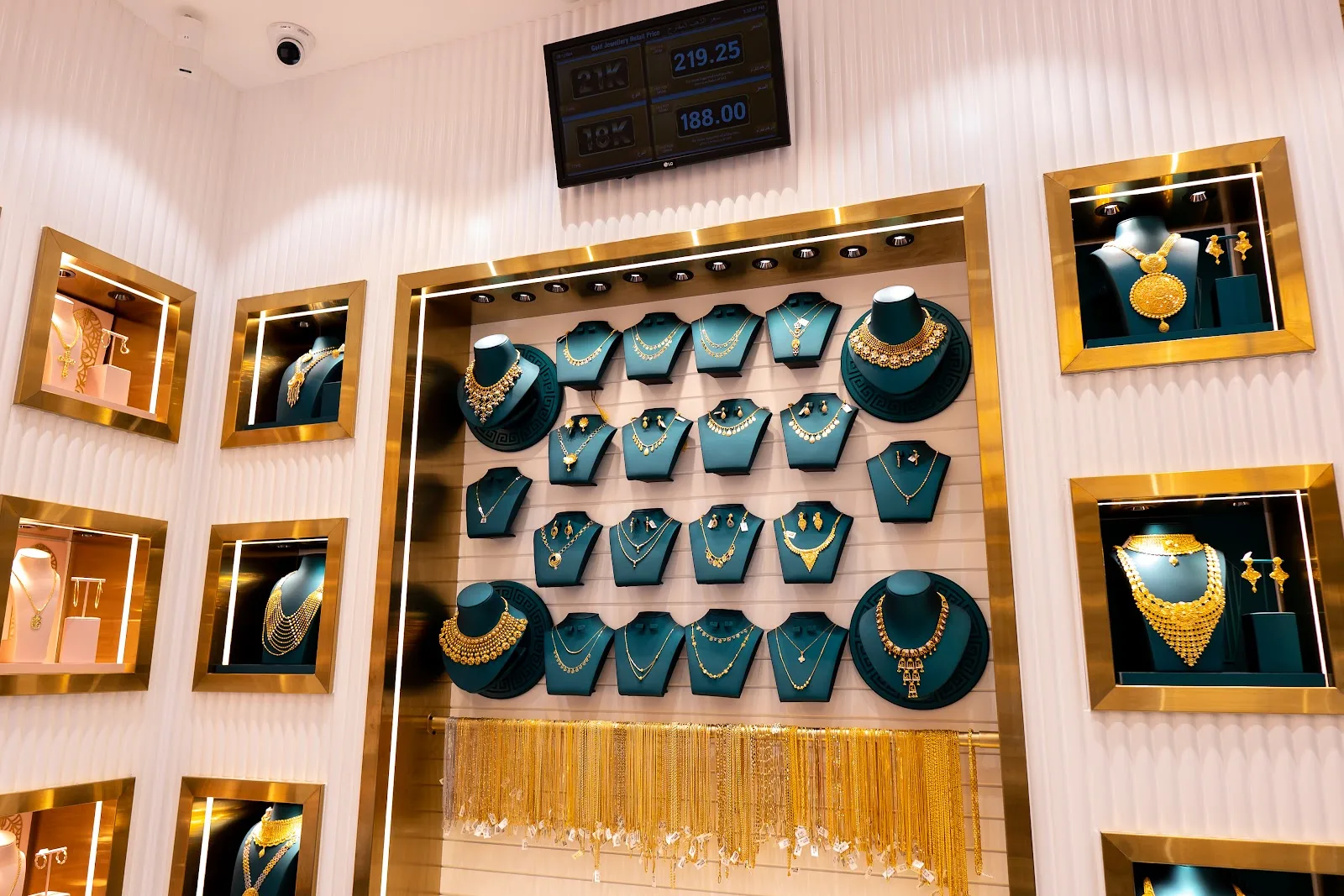 Wall of gold necklace sets on green display busts
