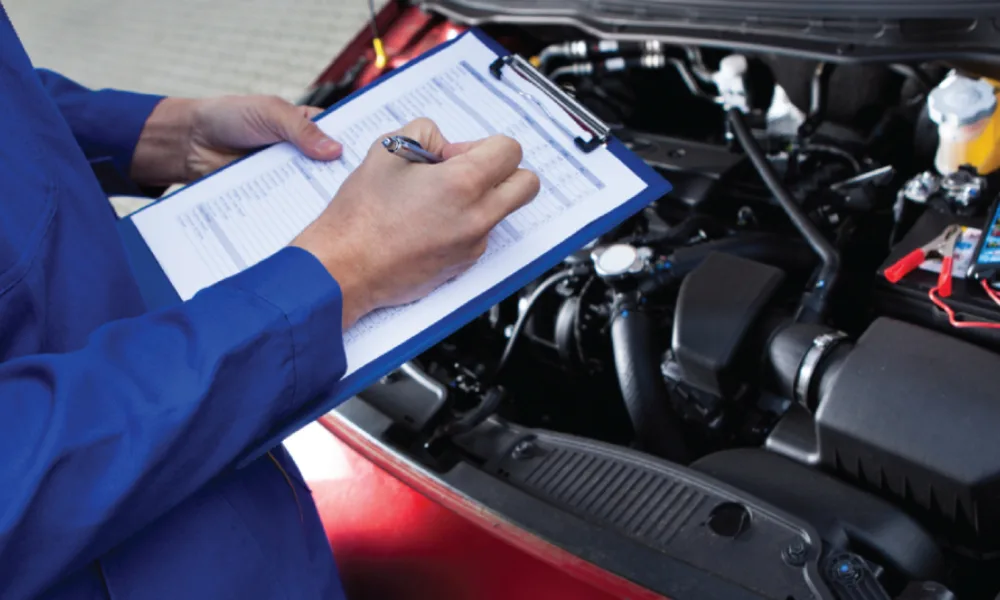 Technician completing an inspection checklist over an open engine bay