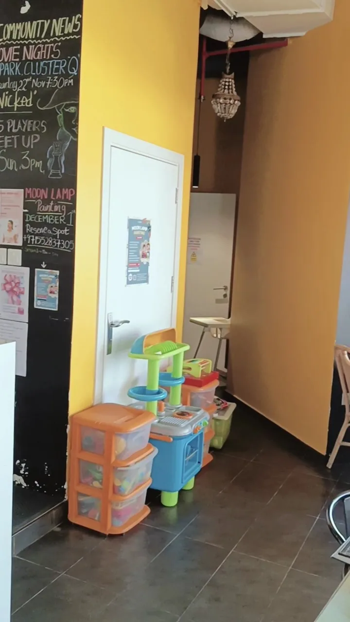 Kids play corner with a toy kitchen beside a yellow community news chalkboard