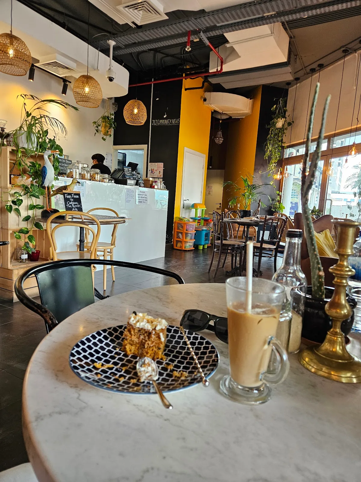 Wide café interior showing the counter, plants, kids play corner and a marble table
