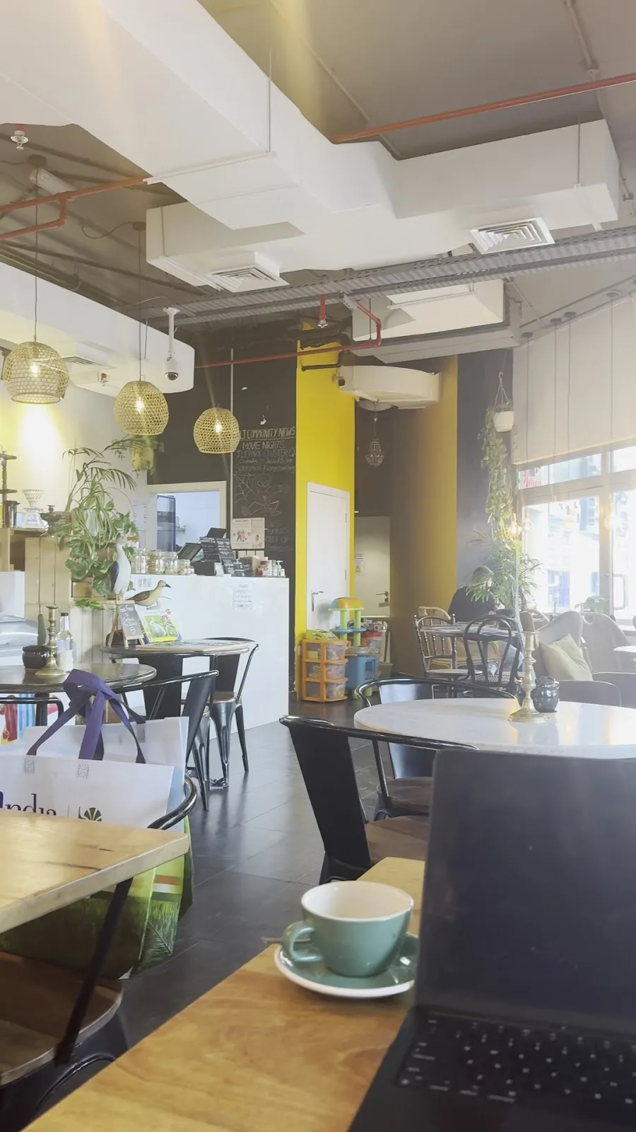 A mint cup of coffee on a café table with plants and hanging lights in the background