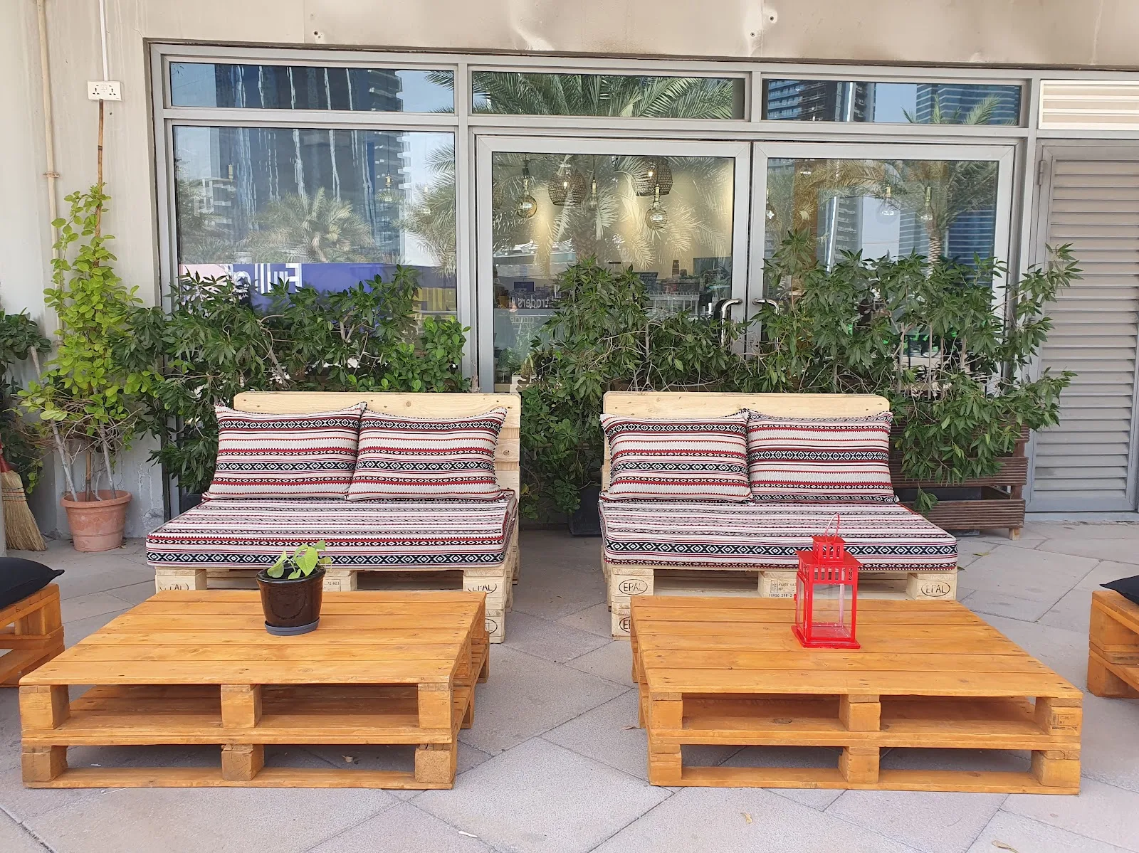 Outdoor terrace with pallet seating and patterned Arabic majlis cushions among plants