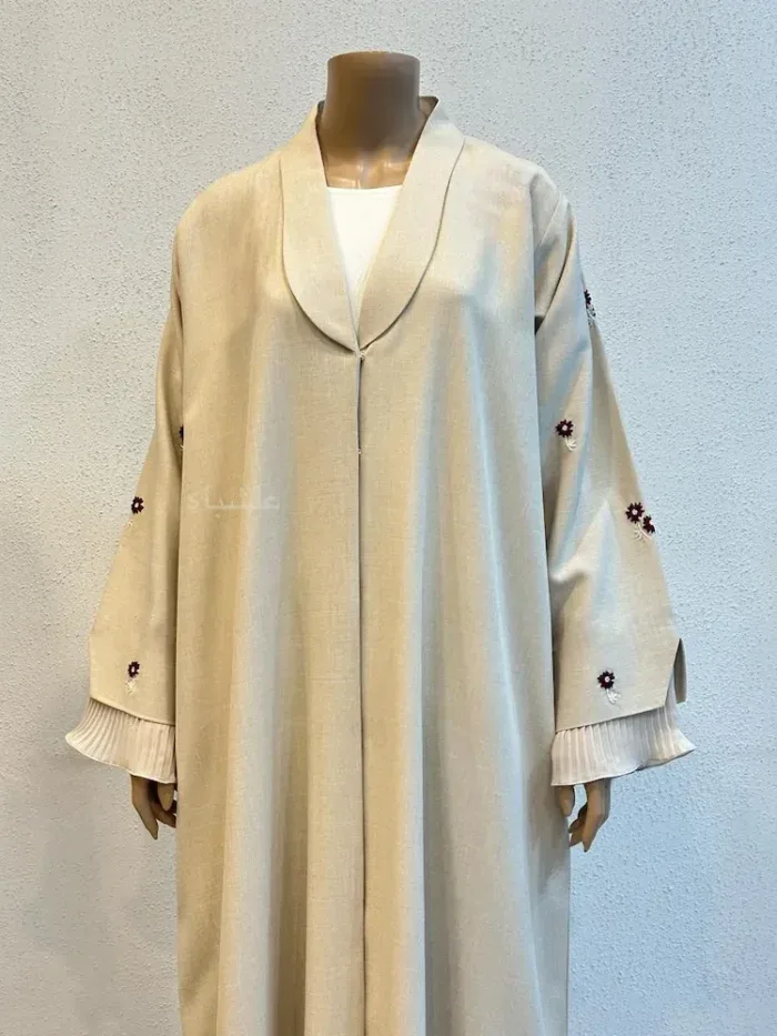 A rail of pastel collared abaya coats with small beaded motifs