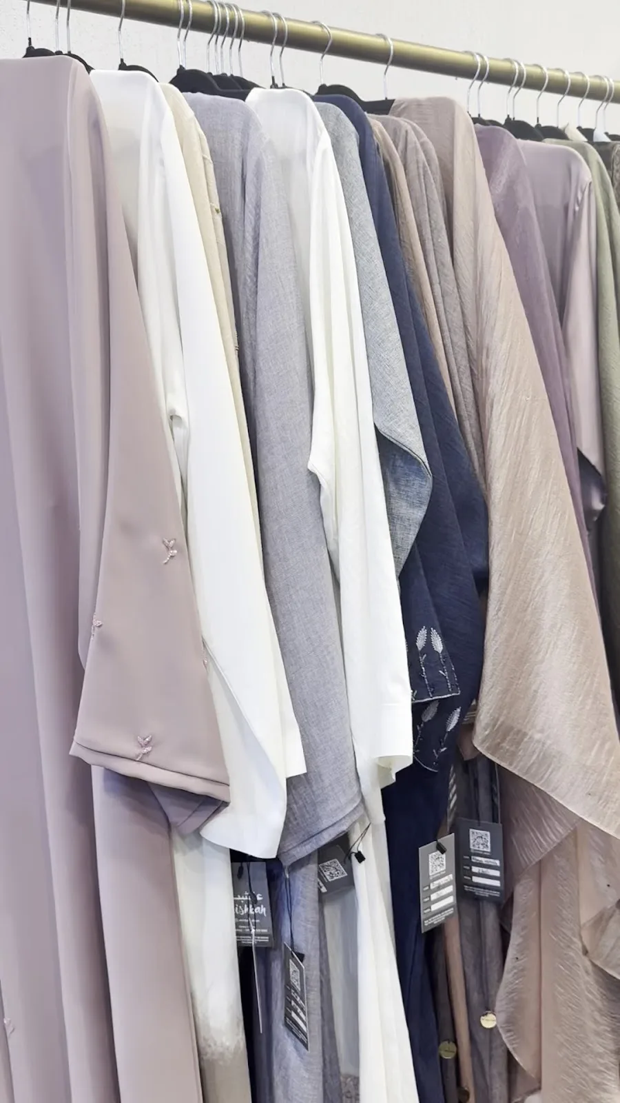 A rail of pastel ready-to-wear abayas with Alishbah hang tags