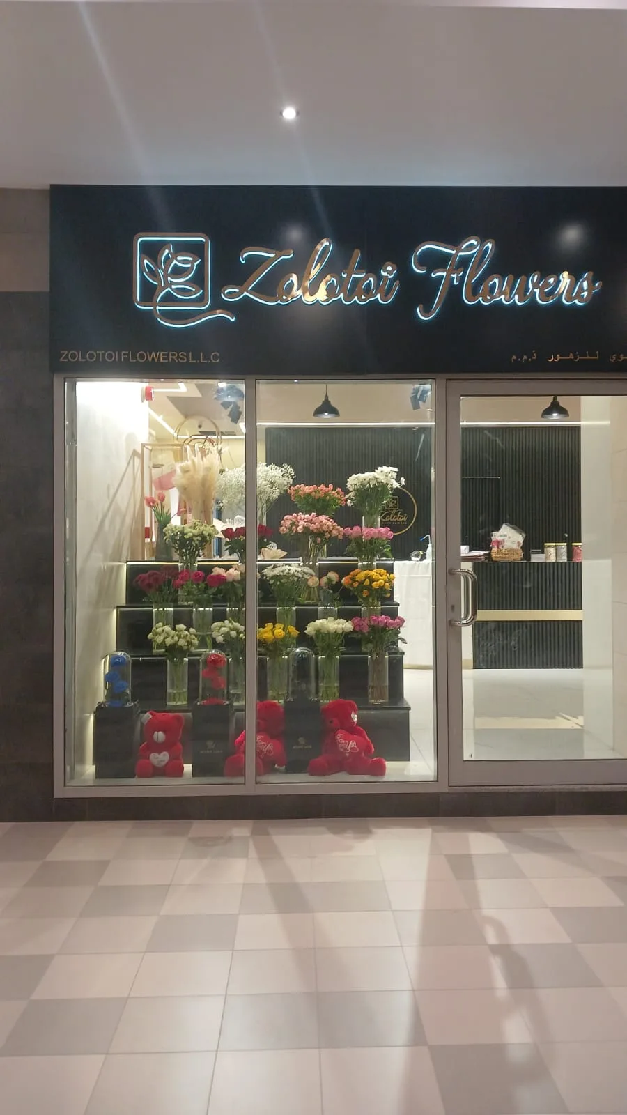 The Zolotoi Flowers shopfront in Business Bay, lit at night with flowers in the window