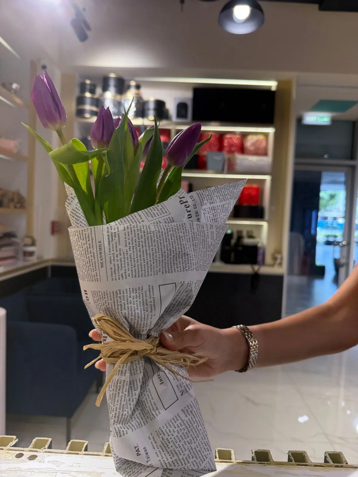 A florist carrying wrapped bouquets outside the Zolotoi Flowers shopfront