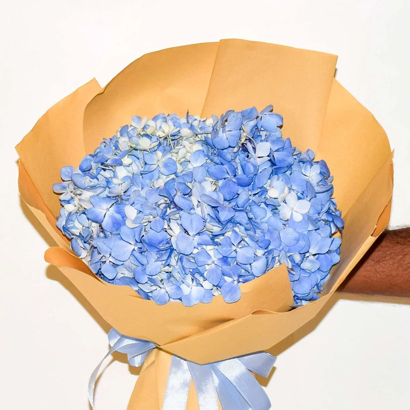 A blue hydrangea bouquet wrapped in kraft paper