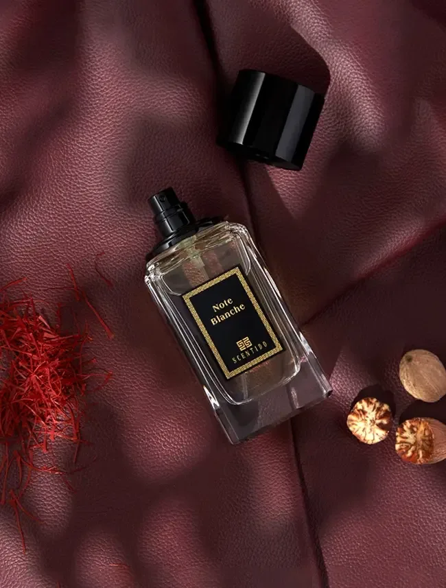 Fragrance bottle on burgundy leather with saffron and nutmeg