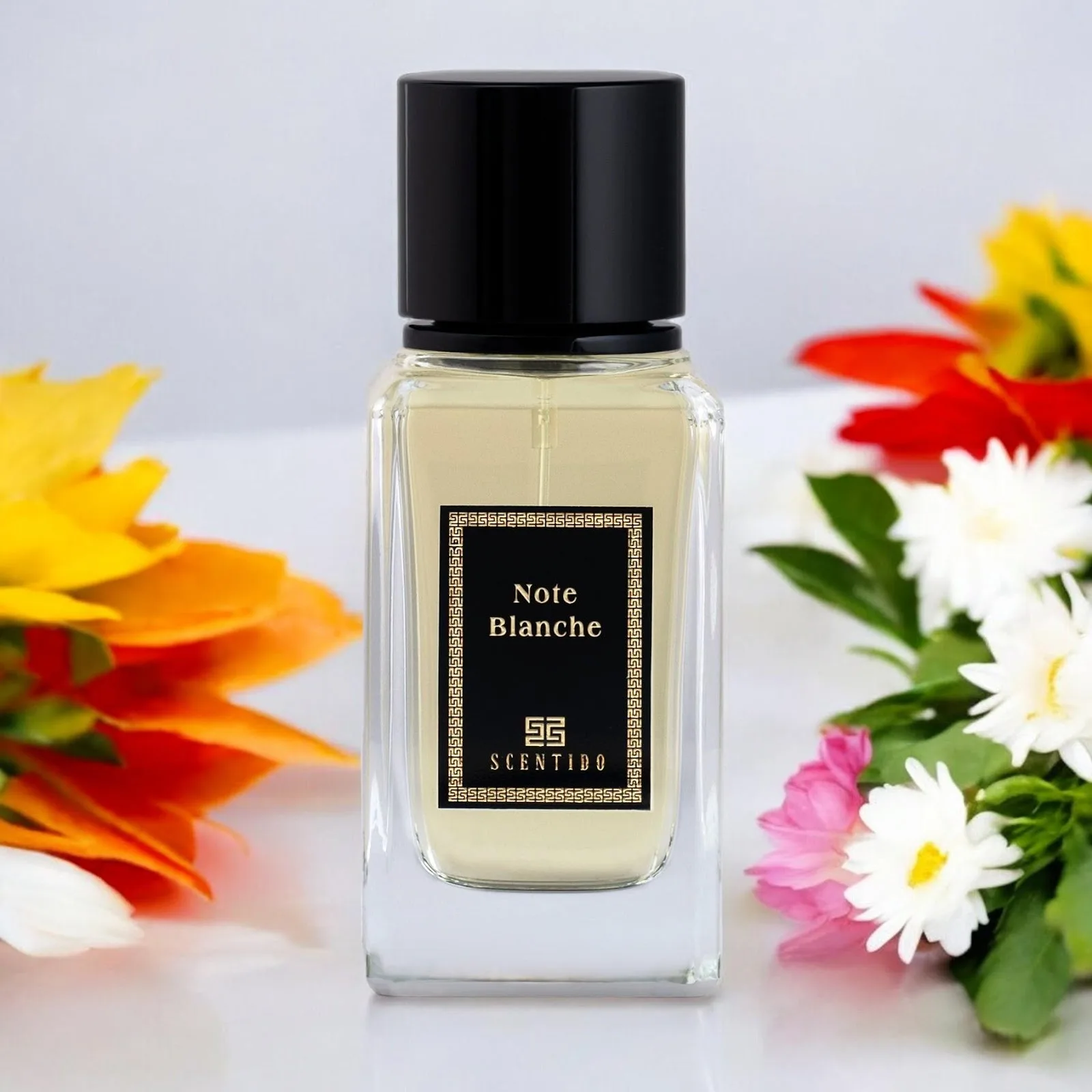 A clear fragrance bottle beside fresh flowers