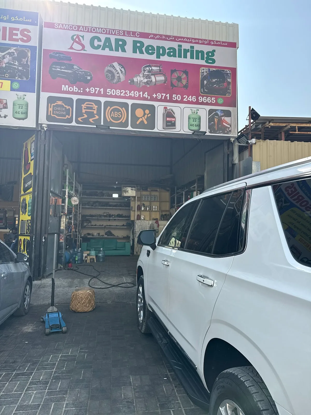 A white SUV parked in front of the open service bays