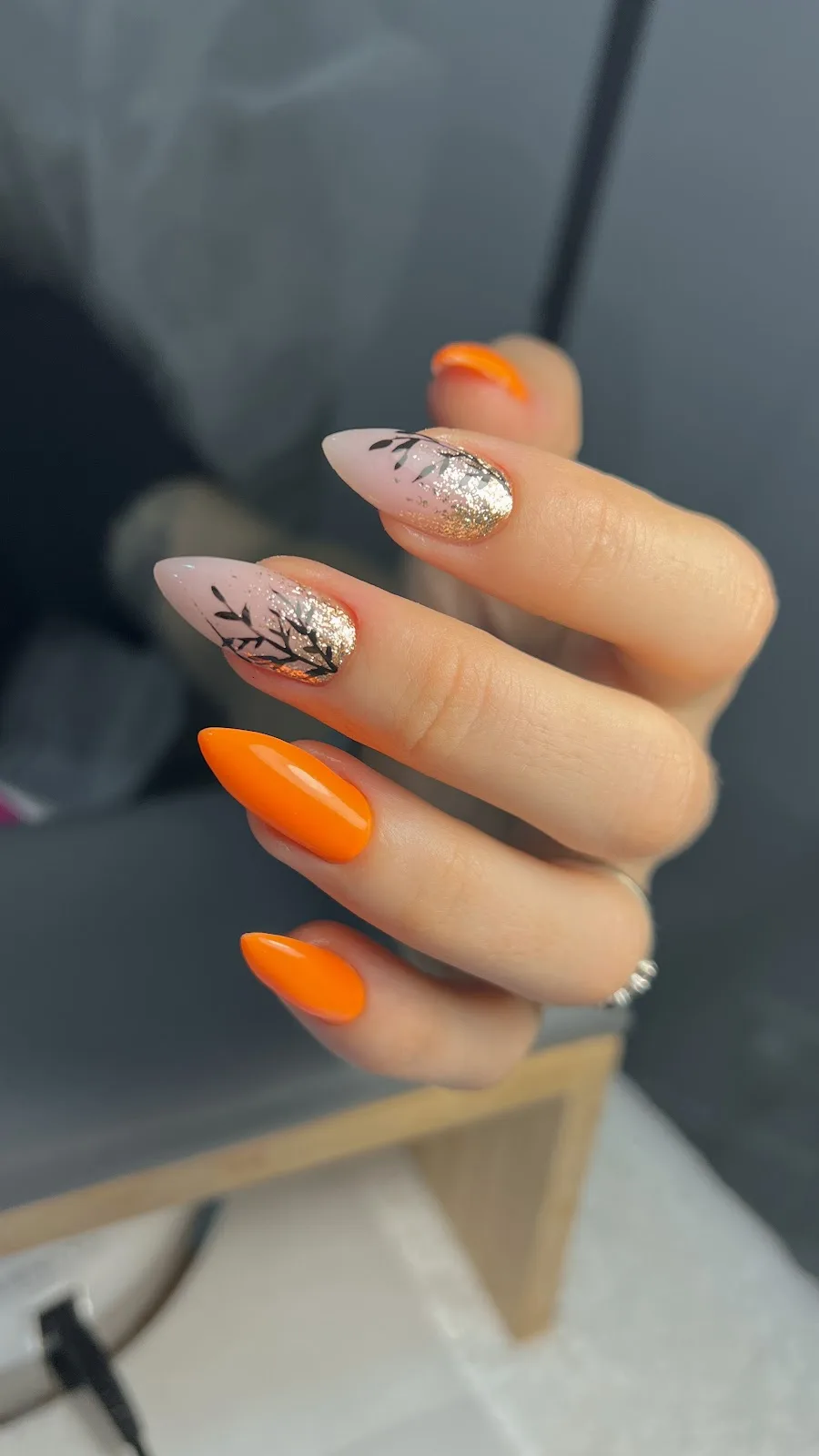 Orange nails with painted leaf and glitter art