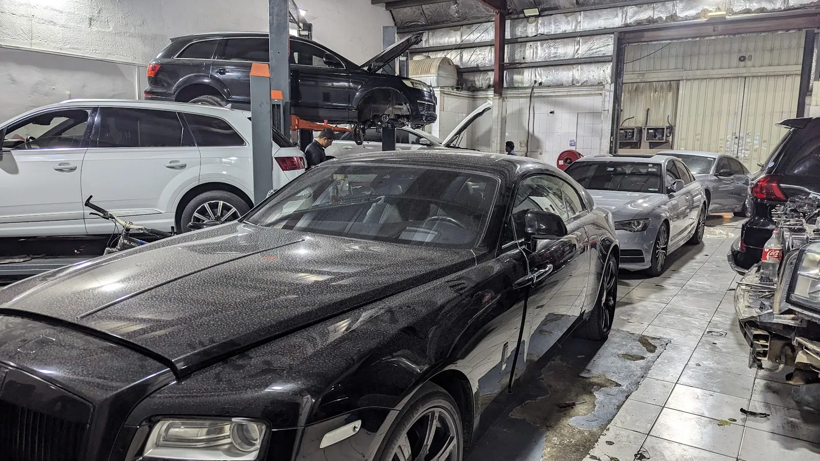 Black Rolls-Royce inside the workshop among other cars