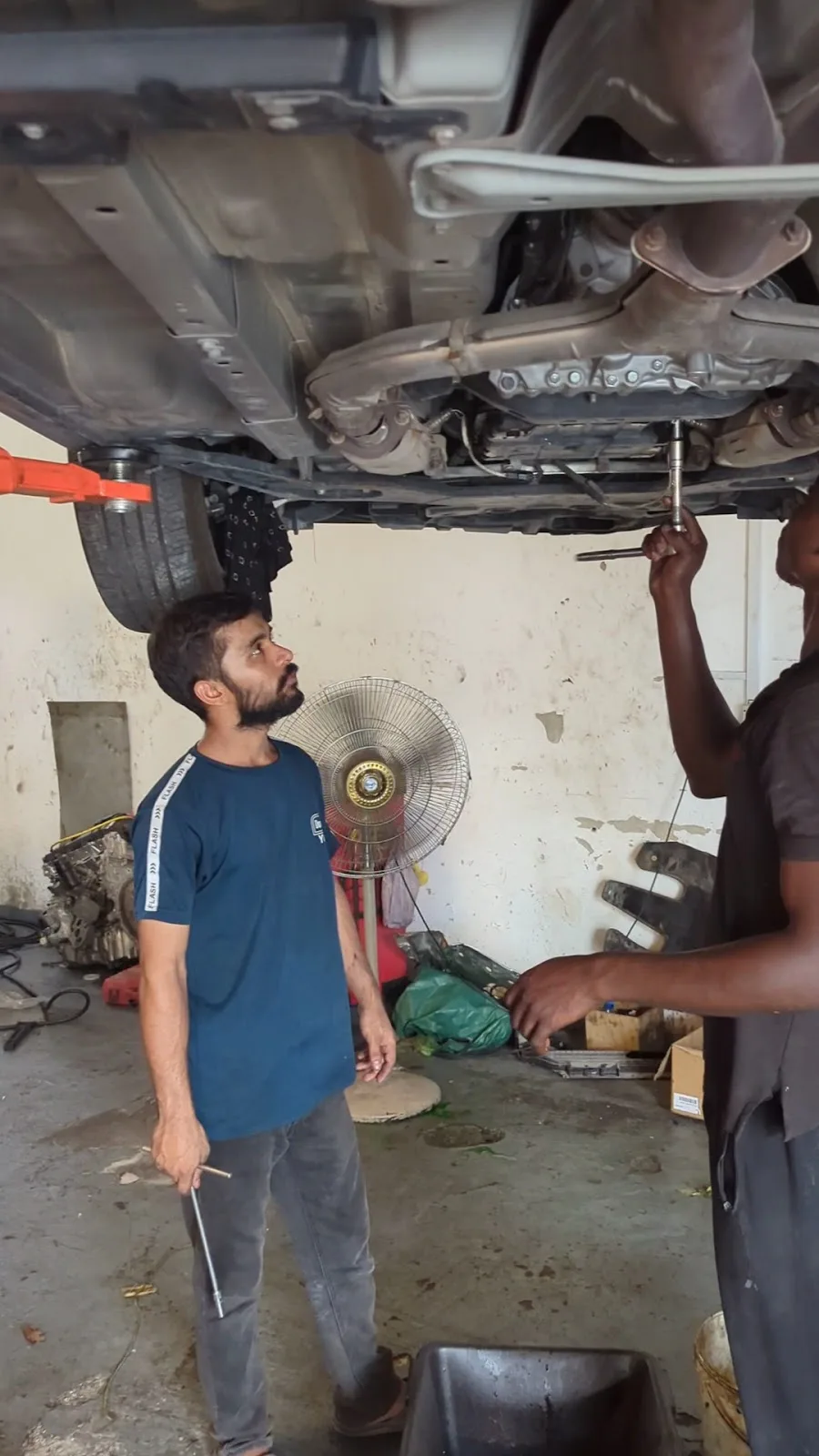 Mechanics working underneath a car on a lift