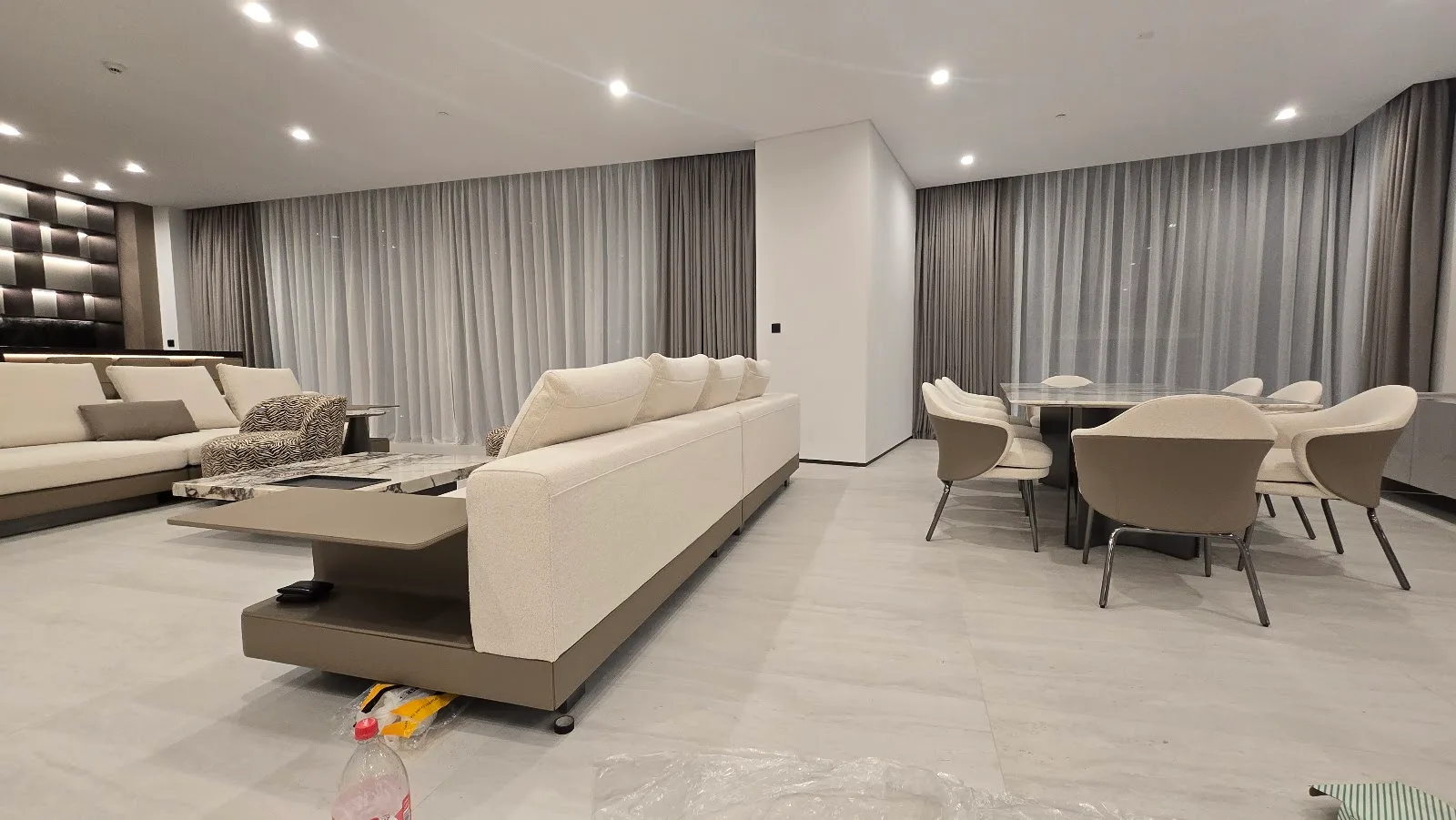 Grey pleated curtains and sheers across a wide living and dining room in Dubai