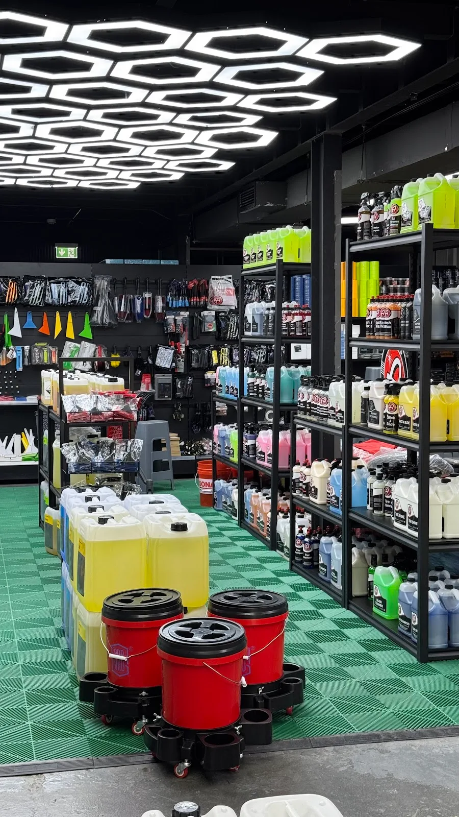 Brightly-stocked product aisles on green floor tiles under hexagon lights