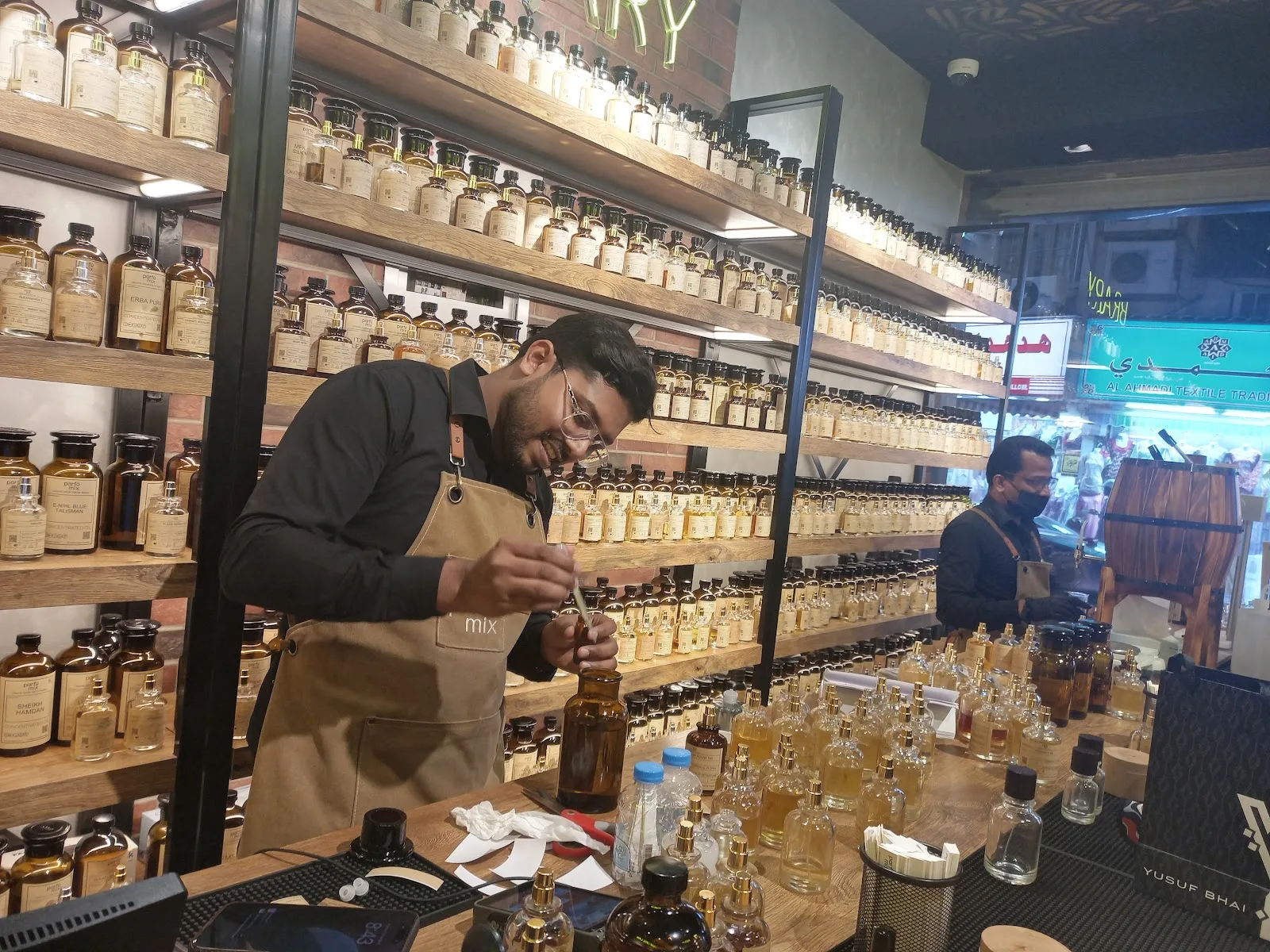 Parfumix perfumer drawing fragrance oil from the brick wall of labelled bottles