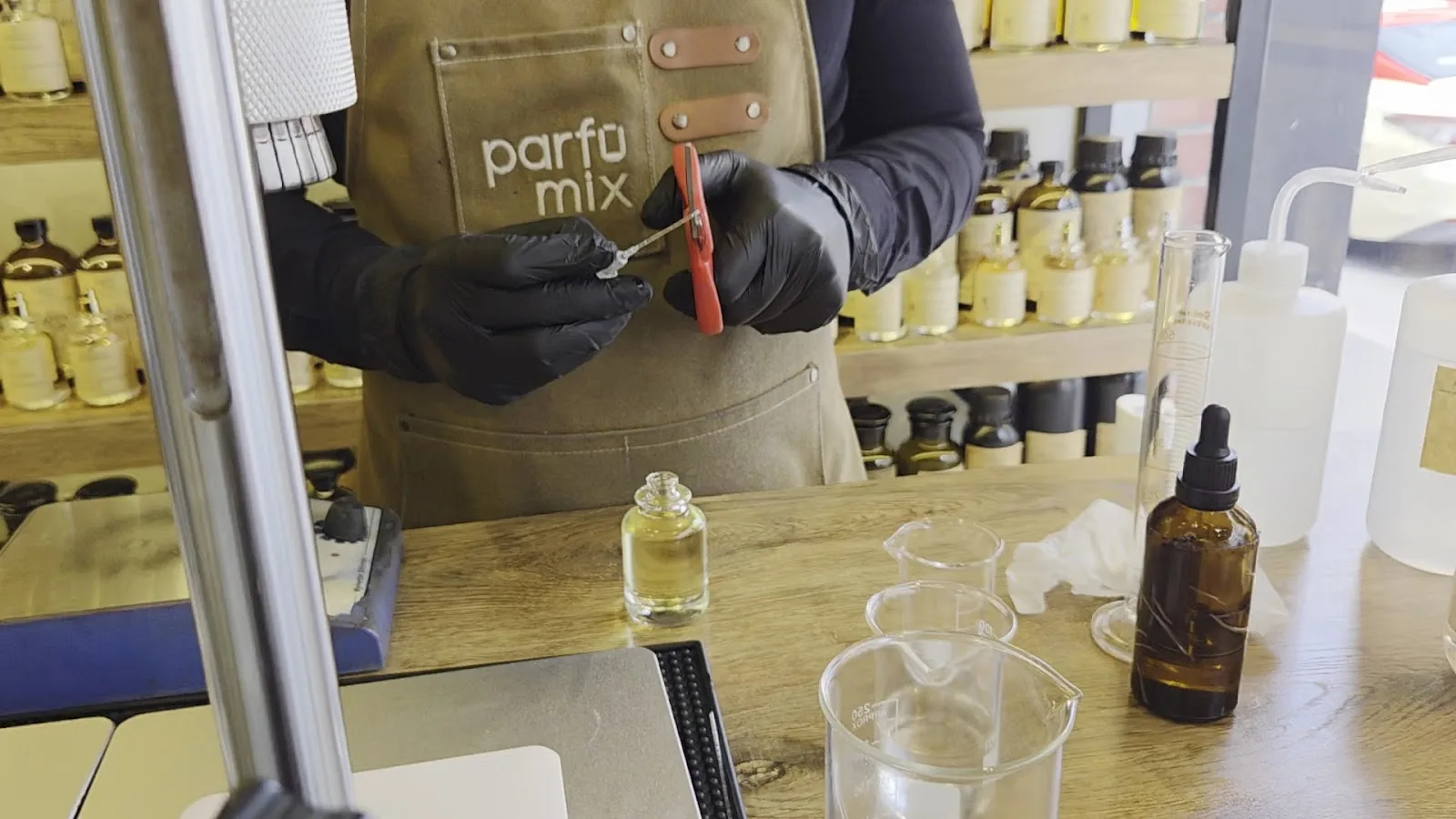 Close-up of gloved hands measuring fragrance with a dropper at Parfumix