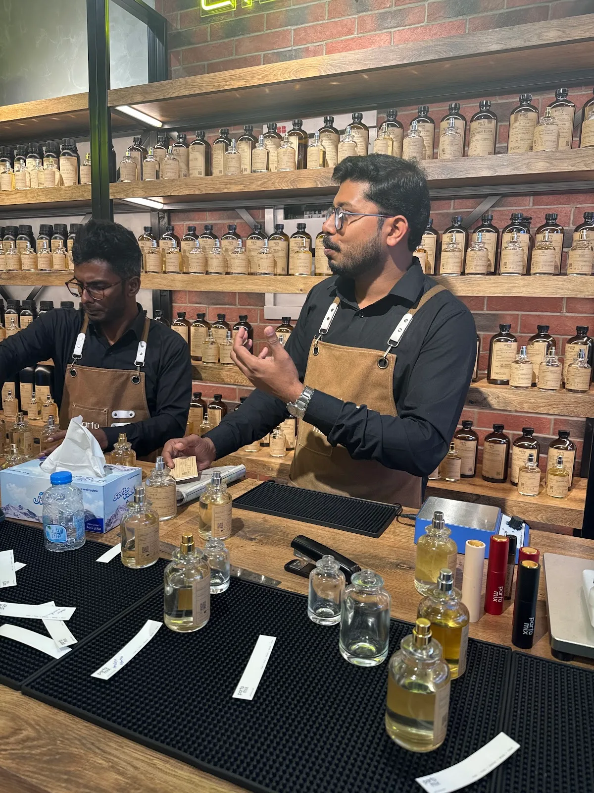 Two Parfumix perfumers in aprons working at the counter