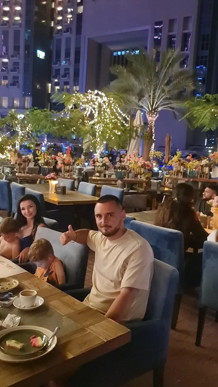 A family seated at the night terrace with flowers, candles and the Marina towers behind them