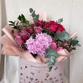 A pink bouquet box of chrysanthemums and roses with eucalyptus