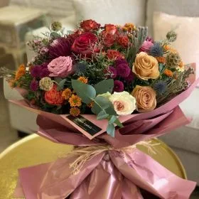 A vivid autumn-toned bouquet with roses and textured fillers