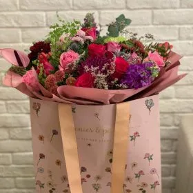 A soft pink bouquet in a branded carrier bag