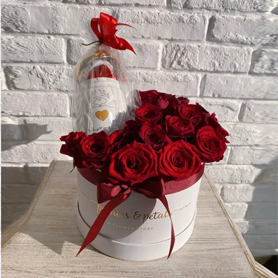 Red roses in a white box paired with a wrapped bottle gift